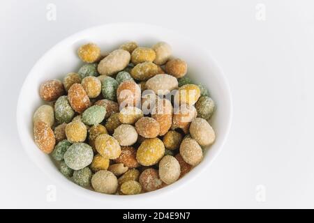 Salted peanuts covered with glaze in a ceramic bowl on a white background. Delicious appetizer. A snack on the way. Close up. Copy space. Stock Photo