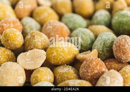 Food background. Macro. Salted peanuts covered with multi-colored glaze. Delicious appetizer. A snack on the way. Selective focus. Copy space. Stock Photo