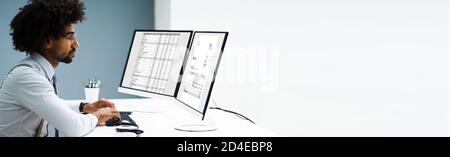 Looking At Invoice And Spreadsheet On Computer At Work Stock Photo