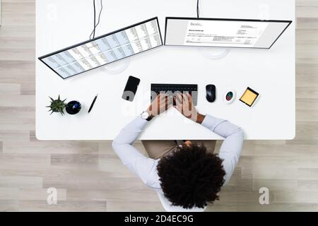Looking At Invoice And Spreadsheet On Computer At Work Stock Photo