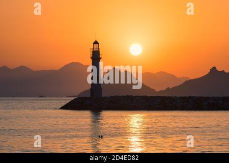 Lighthouse at sunset in harbour Stock Photo