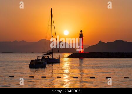 Lighthouse at sunset in harbour Stock Photo