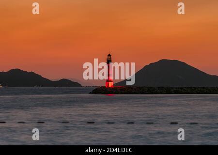 Lighthouse at sunset in harbour Stock Photo