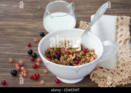 Homemade delicious healthy granola with nuts, seeds, honey and fresh berries in a ceramic cup on a wooden table Stock Photo