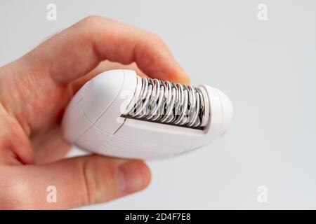 Epilator in a female hand on a white background. Hair removal device Stock Photo