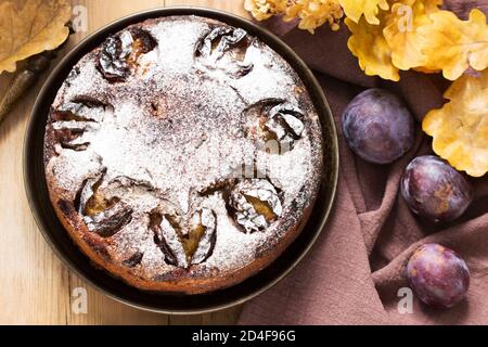 Plum pie with nuts and chocolate on a wooden background. Rustic style. Stock Photo