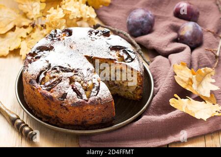Plum pie with nuts and chocolate on a wooden background. Rustic style. Stock Photo