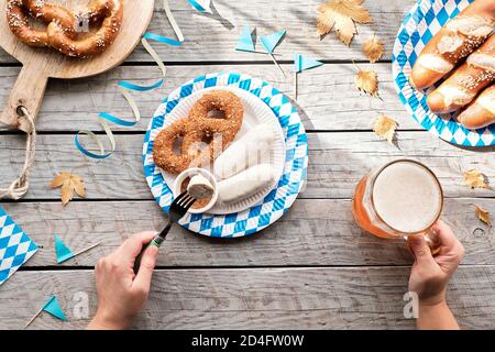 Celebrating Oktoberfest alone. Traditional food and beer, weisswurst sausage and pretzels. Stock Photo