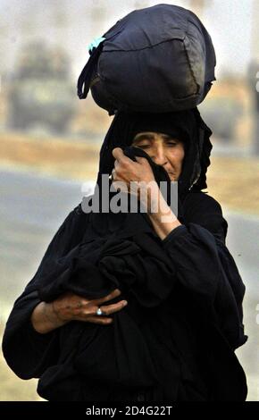 An Iraqi woman, a refugee from the Baghdad area, carries a small bag on her head as she walks on the road southeast of the Iraqi capital Baghdad on April 6, 2003. A heavy artillery barrage thundered on Sunday from Daura, a southeastern suburb of Baghdad which contains an oil refinery, a Reuters witness said. Planes roared over the Iraqi capital as the sound of artillery fire echoed from Daura, which includes an electricity power grid as well as the oil refinery, Reuters correspondent Samia Nakhoul said in central Baghdad. REUTERS/Oleg Popov REUTERS  OP/