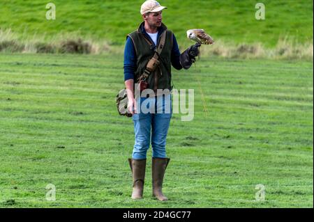 A falconer with a barn owl giving a ‘Birds of Prey’ display at National Centre for Birds of Prey (NCBP) in the grounds of Duncombe Park in a small mar Stock Photo