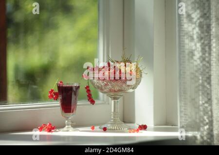 Red and white currant fruits and juice in glass on the window Stock Photo