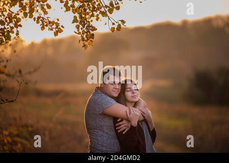 Happy lovers hold hands, hug each other, kiss, spend time together. A young man and a girl are walking in the autumn forest.  Traveling Couple in love Stock Photo