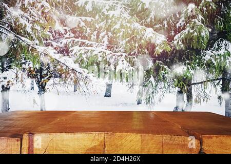 Empty rustic woooden table top with blurred spruce trees with snow on the background. Mock up banner for display of advertise product Stock Photo