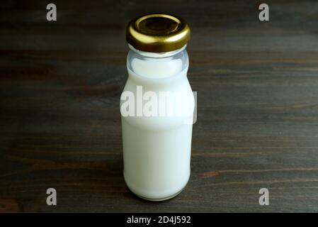 Glass bottle of Milk isolated on dark brown wooden background Stock Photo