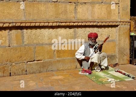 A man wearing turban is siting on ground and playing vilolin at Jaiselmer Rajasthan India on 21 February 2018 Stock Photo