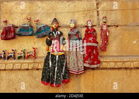 Colorful human shaped Puppets wearing colorful clothes hanging against the wall in Rajasthan India on 21 February 2018
