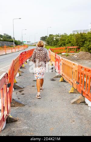 Pedestrian woman passing through Roadworks at on the Sallins road near Johnstown in County Kildare, Ireland Stock Photo