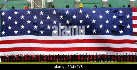 Members of all the United States armed services stand underneath a giant United States flag draped across Fenway Park's famed 'Green Monster' left field wall as the U.S. national anthem is played before the Red Sox scheduled home opener game April 11, 2003 in Boston. The baseball game between the Boston Red Sox and the Baltimore Orioles was called off and delayed until another day due to heavy rain. REUTERS/Jim Bourg REUTERS  JRB