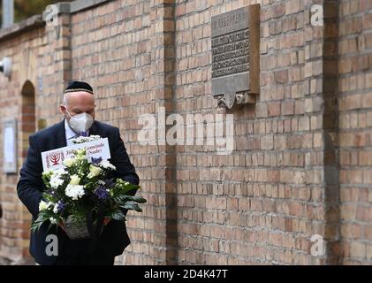 Halle, Germany. 09th Oct, 2020. Max Privorozki, chairman of the Jewish Community of Halle, lays flowers at a memorial plaque for the victims of the attack in Halle/Saale in front of the synagogue. One year after the right-wing terrorist attack on the highest Jewish holiday Yom Kippur in Halle, the victims are commemorated with events and prayers. Credit: dpa picture alliance/Alamy Live News Stock Photo