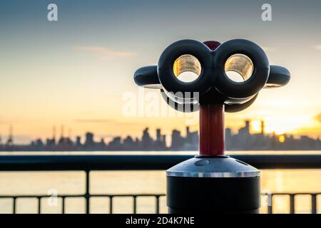 Binoculars with skyline of city. Sunset lighting. Blurred view of downtown Vancouver, BC, Canada, from Lonsdale Quay, North Vancouver. Geometric binoc Stock Photo