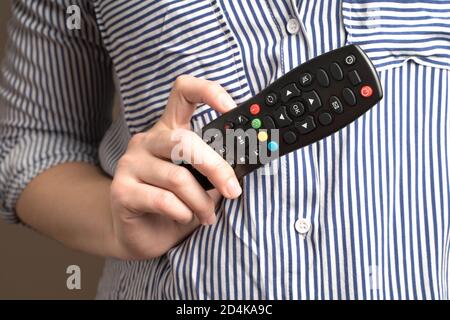 A woman holding a remote control, side view. Stock Photo