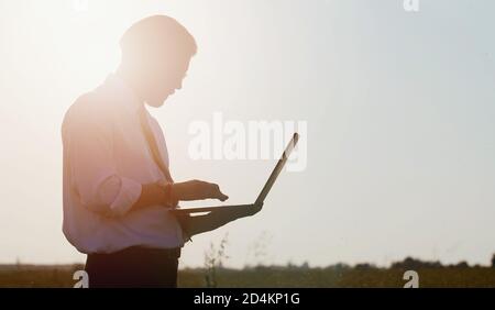 Businessman holding laptop standing countryside Stock Photo