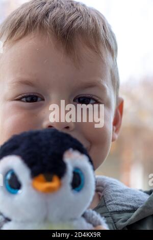 Young boy playing with stuffed animal penguin Stock Photo