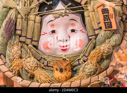 asakusa, japan - november 08 2019: Giant auspicious rake made of straw and papier-mâché decorated with the Okame face of the Otafuku goddess of mirth, Stock Photo