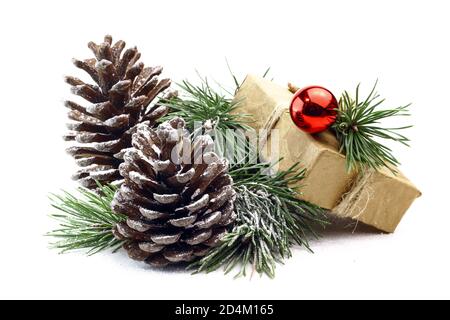 Snowy spruce branch with fir cones and gift box isolated on white background. Christmas and holiday concept image with gift box and fir cones. Stock Photo