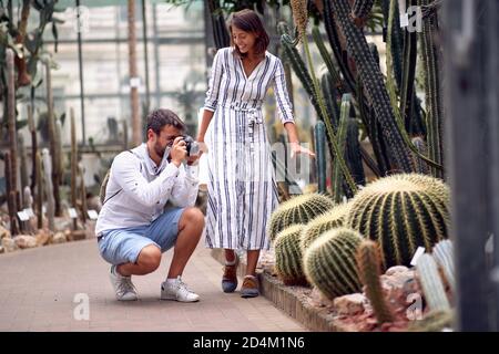 Male visitor with female guide taking photo of giant cactuses at the conservatory Stock Photo