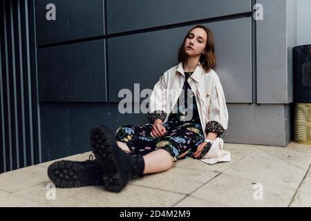 Woman sitting on concrete floor near building Stock Photo