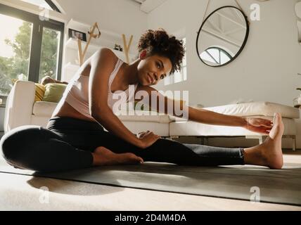 Woman exercising at home, stretching legs and warming up  Stock Photo