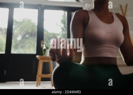 Young female yogi in calm position sitting on gym mat in modern lounge. Stock Photo
