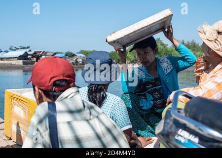 Chaung Thar, Myanmar - December 26, 2019: Portrait of three unidentified women with thanaka on their faces, one holds styrofoam for shade Stock Photo