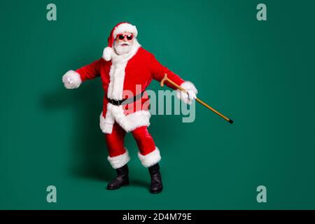 Full length body size view of his he nice attractive cheerful cheery Santa holding in hand cane having fun dancing enjoying rest celebration festal Stock Photo