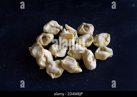 Fresh Ravioli on floury dark background. Italian homemade healthy food concept.Process of making italian ravioli. Stock Photo