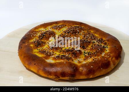 Turkish Ramadan Pide. It is a kind of leavened, flat bread in Turkish cuisine. sprinkled with scrambled eggs, sesame seeds and doughnut on top Stock Photo