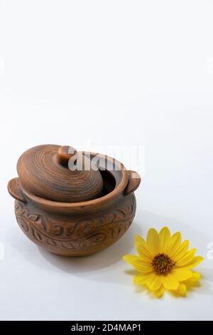 Brown clay pot with lid for cooking. A sleek vintage baking pot. Beautiful utensils for the kitchen and table setting. Shallow depth of field. Stock Photo