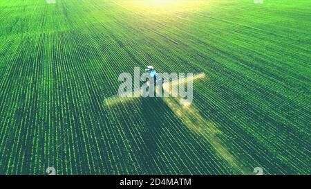 Tractor spray fertilizer on green field drone high angle view, agriculture background concept. Stock Photo