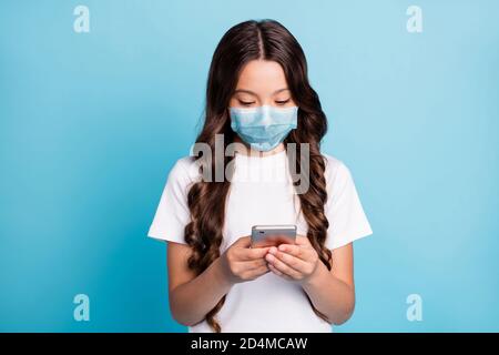 Close-up portrait of her she focused wavy-haired girl using digital device gadget share covid spread news wear medical mask isolated on bright vivid Stock Photo