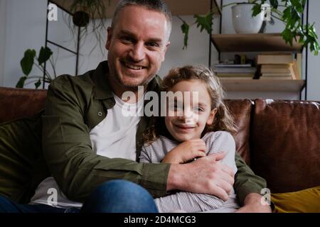 Father and daughter cuddling on the sofa and bonding with one another at home Stock Photo