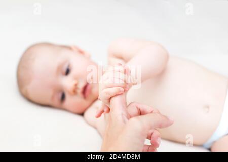 Cute baby girl holding mothers finger