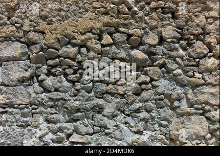 Old wall constructed from different types and sizes of stones and rocks. Background image Stock Photo