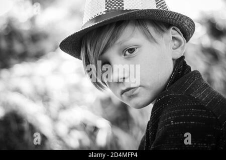 Fair-haired kid playing with leaves and looking at camera. Sale for entire autumn collection, incredible discounts and wonderful choice. Bye summer - Stock Photo