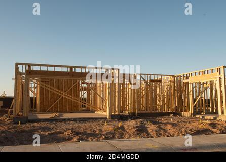 A partial view of a new house construction showing the wood frame before the siding and roofing stands in early morning light on a dirt lot, horizontal view.