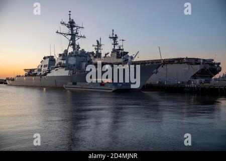 201008-N-KU319-1001  NORFOLK, Va. (Oct. 8, 2020) – The Arleigh-Burke class guided missile destroyer USS Cole (DDG 67) and the Wasp-class amphibious assault ship USS Iwo Jima (LHD 7) sit pier-side at Naval Station Norfolk, Virginia during sunset, Oct. 8, 2020. Cole was the target of a terrorist attack in Yemen October 12, 2000. This year her crew commemorates the 20 years of this attack and the remembers the 17 Sailors who were lost, as well as the Sailors who survived. The ship is named in honor of Darrell S. Cole, a machine-gunner killed in action on Iwo Jima on 19 February 1945, during World Stock Photo