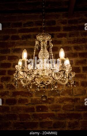 Crystal chandelier, antique lamp on the background of the brown brick wall.  Stock Photo