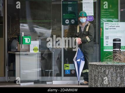 Vancouver, Canada. 9th Oct, 2020. A man wearing a face mask waits for banking service outside a bank in Vancouver, British Columbia, Canada, Oct. 9, 2020. According to a new COVID-19 modeling report issued by the Canadian government on Friday. The total of Canadian COVID-19 is on track to hit between 188,150 and 197,830 cases, and between 9,690 and 9,800 deaths as of Oct. 17. As of Friday noon, there were a total of 177,613 COVID-19 cases and 9,583 deaths, according to CTV. Credit: Liang Sen/Xinhua/Alamy Live News Stock Photo
