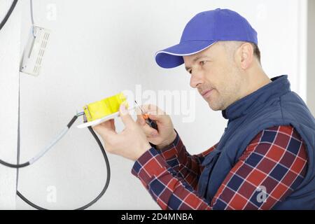 worker trying to install wires on the wall Stock Photo