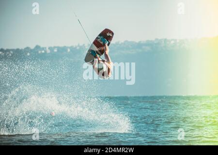 WAKEBOARDING AT THE SEA JUMPING HIGH DOING A BACKFLIP. Stock Photo